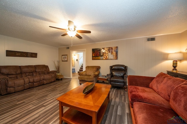 living room featuring ceiling fan, a textured ceiling, and dark hardwood / wood-style flooring