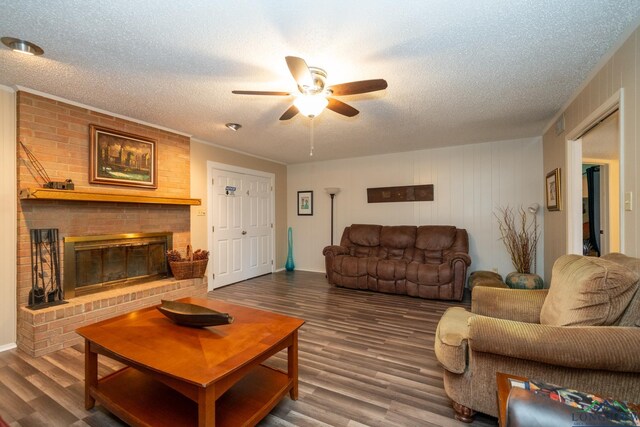 living room with ceiling fan, a fireplace, hardwood / wood-style floors, and a textured ceiling