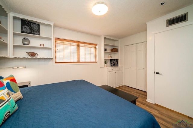 bedroom with dark wood-style floors, a closet, a textured ceiling, and visible vents