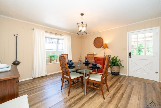 dining room featuring a notable chandelier, crown molding, baseboards, and wood finished floors