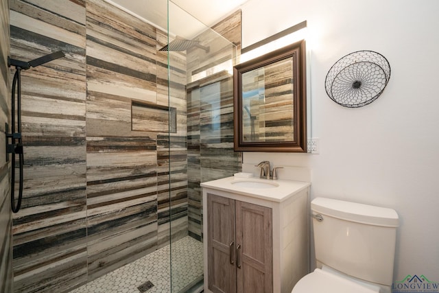 bathroom featuring a tile shower, vanity, and toilet