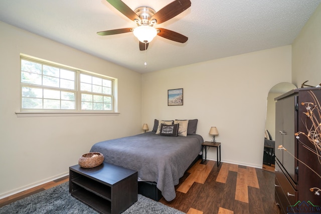 bedroom featuring dark hardwood / wood-style flooring, a textured ceiling, and ceiling fan