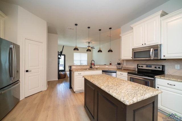 kitchen with white cabinetry, a center island, kitchen peninsula, pendant lighting, and appliances with stainless steel finishes