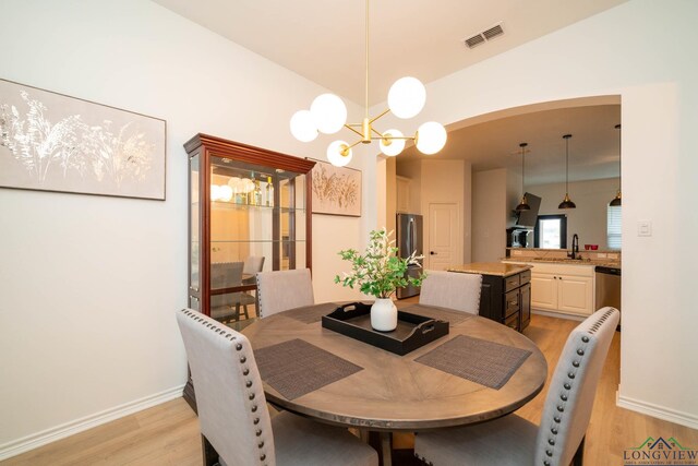 dining area with light hardwood / wood-style flooring, a notable chandelier, and sink