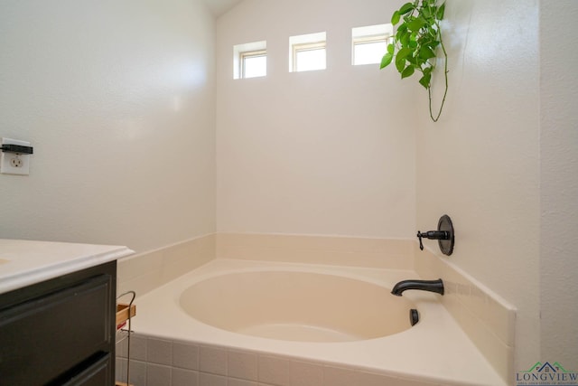 bathroom with vanity and tiled tub