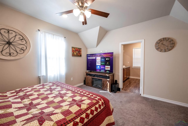 carpeted bedroom with ensuite bath, ceiling fan, and vaulted ceiling