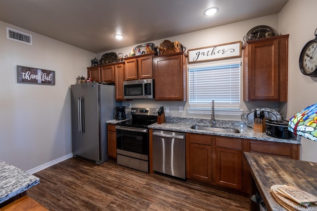 kitchen featuring light stone countertops, dark hardwood / wood-style flooring, stainless steel appliances, and sink