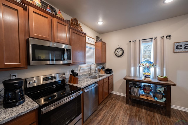 kitchen featuring light stone countertops, sink, dark wood-type flooring, and appliances with stainless steel finishes