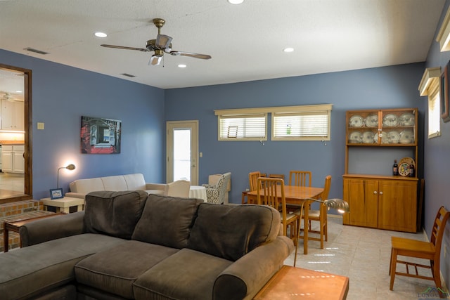 living room featuring ceiling fan, light tile patterned floors, and a textured ceiling