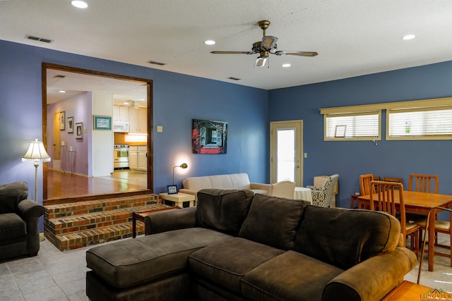 living room featuring light tile patterned floors, a textured ceiling, and ceiling fan