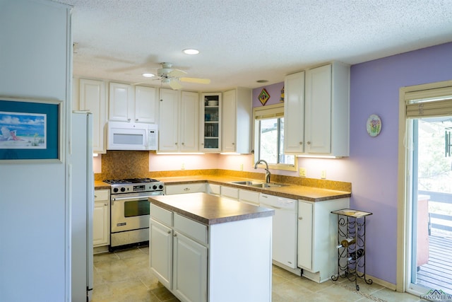 kitchen with a textured ceiling, white cabinets, a kitchen island, and white appliances