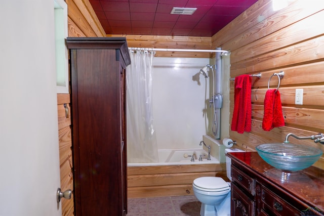 full bathroom with tile patterned floors, vanity, shower / bath combo with shower curtain, wooden walls, and toilet