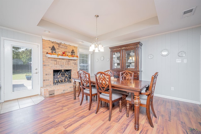 dining area with a fireplace, a tray ceiling, and wood-type flooring