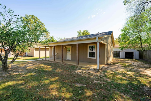 back of property featuring a storage unit, a yard, and a patio