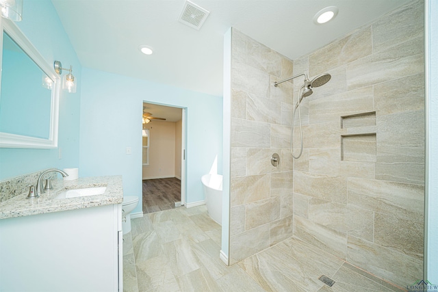 bathroom featuring vanity, ceiling fan, toilet, and a tile shower