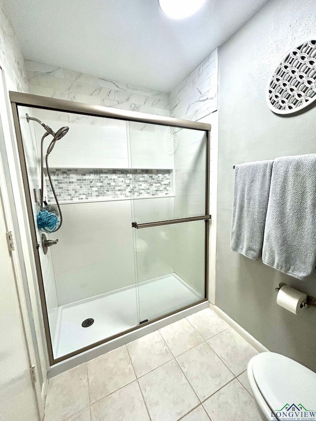 bathroom with tile patterned flooring, toilet, and walk in shower