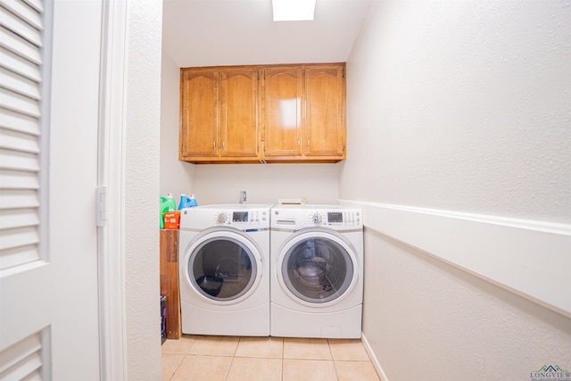 washroom featuring light tile patterned floors, cabinets, and washer and dryer