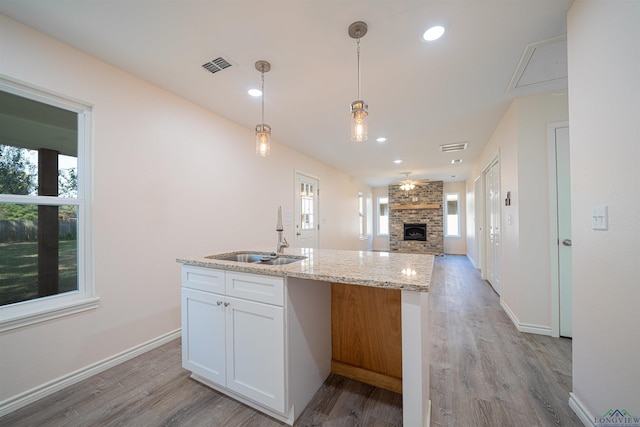 kitchen featuring sink, ceiling fan, white cabinetry, light stone countertops, and decorative light fixtures