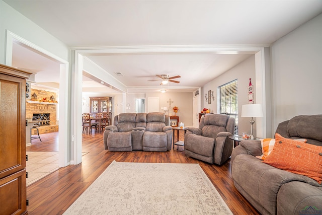 living room with ceiling fan, dark hardwood / wood-style floors, and a brick fireplace