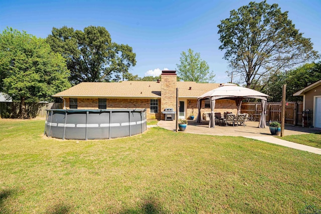 back of property with a fenced in pool, a gazebo, a lawn, and a patio area