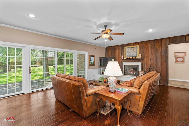 106 Brachfield Rd, Henderson, TX 75654 - living room featuring a ceiling fan, crown molding, dark wood-type flooring, wood walls, and a brick fireplace