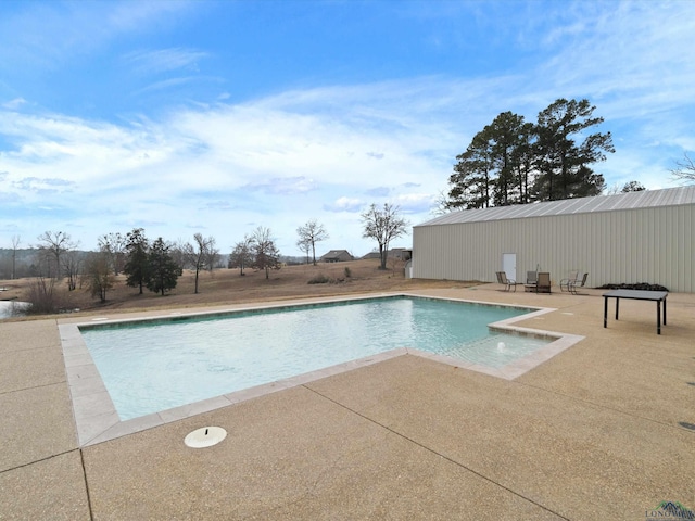 view of pool with a patio and an outbuilding