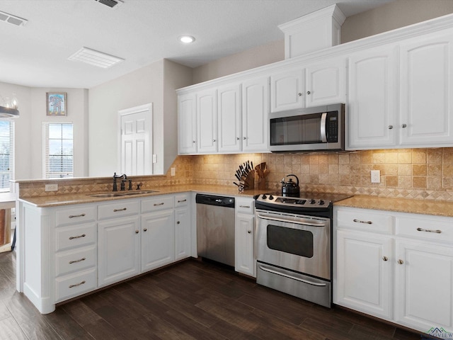 kitchen featuring sink, dark hardwood / wood-style flooring, kitchen peninsula, stainless steel appliances, and white cabinets