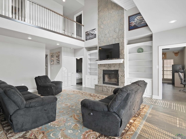 living room with built in shelves, a towering ceiling, and a fireplace