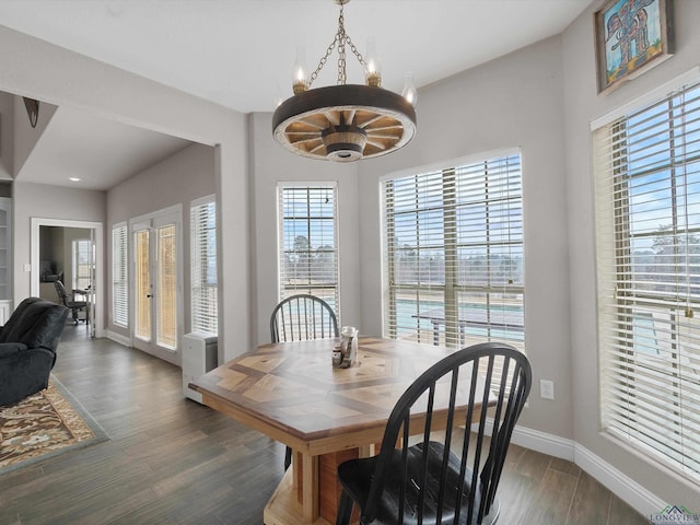 dining room with dark wood-type flooring, an inviting chandelier, and french doors