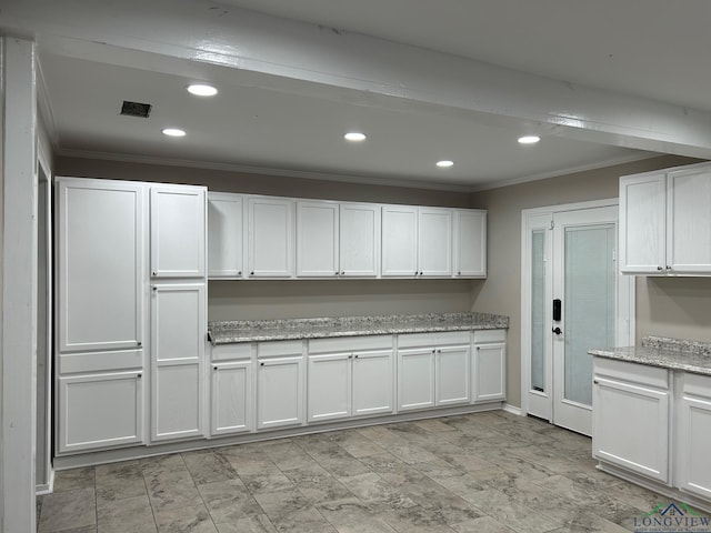 kitchen with light stone countertops, white cabinetry, and crown molding