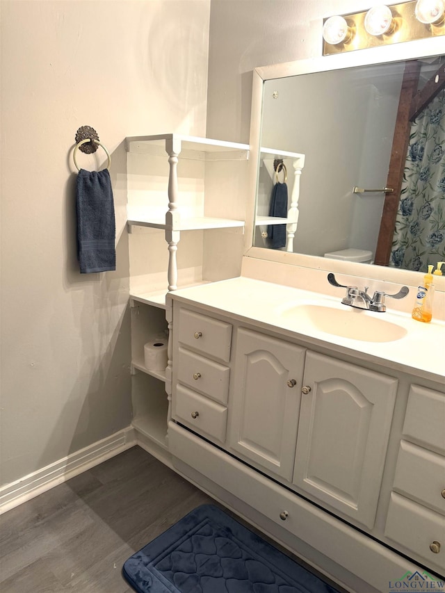 713 Martha Dr, Gladewater, TX 75647 - bathroom featuring wood finished floors, vanity, toilet, and baseboards