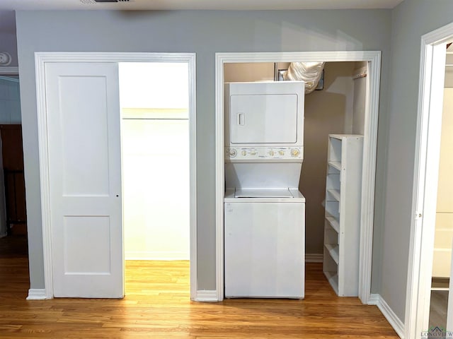 713 Martha Dr, Gladewater, TX 75647 - laundry room with stacked washer / dryer, light wood-style flooring, and baseboards