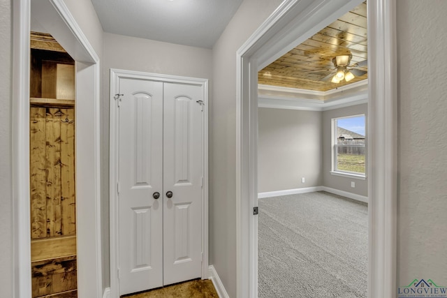 corridor featuring carpet, a raised ceiling, and wood ceiling