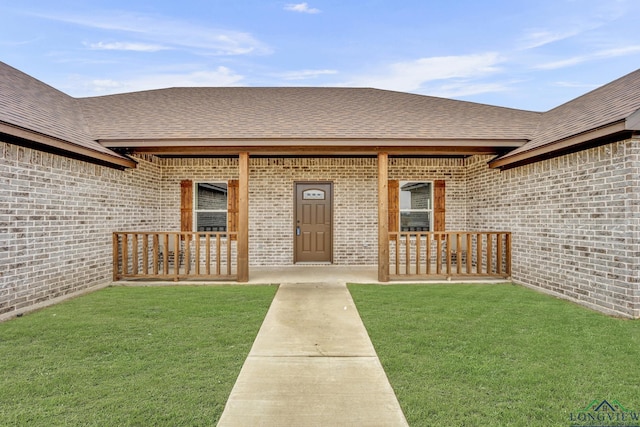 doorway to property with a lawn and a porch