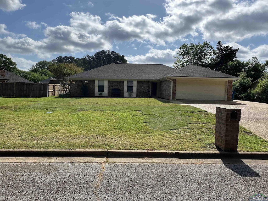 ranch-style house featuring fence, a front lawn, brick siding, an attached garage, and driveway