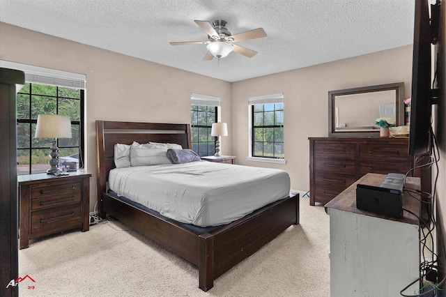 carpeted bedroom with multiple windows, a ceiling fan, and a textured ceiling