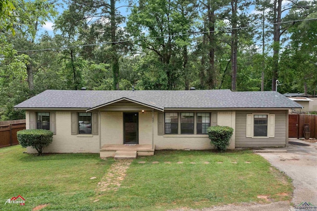 ranch-style house with fence, a shingled roof, brick siding, and a front yard