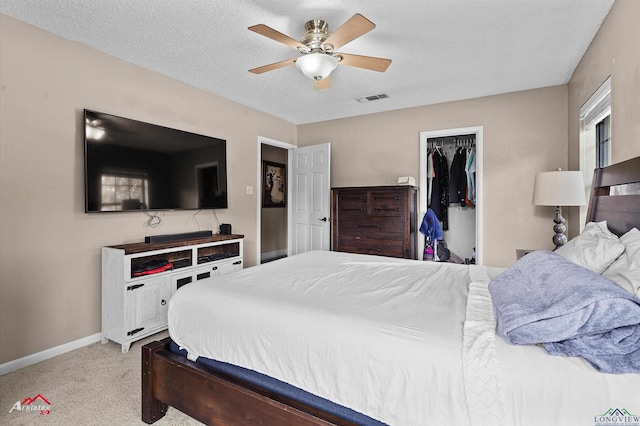 bedroom featuring a walk in closet, visible vents, baseboards, a closet, and light carpet