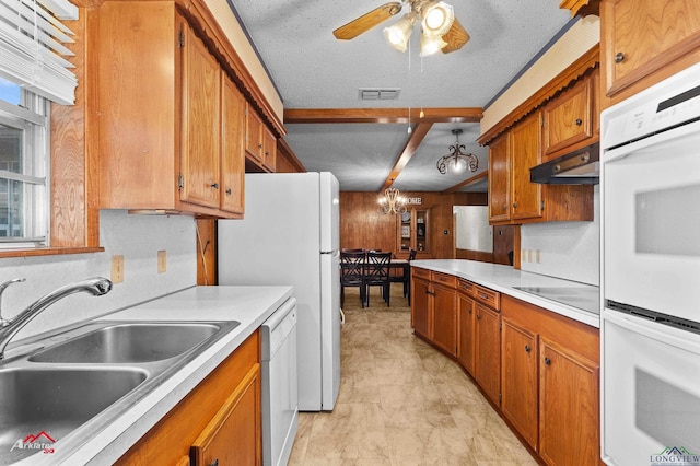 kitchen with white appliances, visible vents, light countertops, under cabinet range hood, and a sink