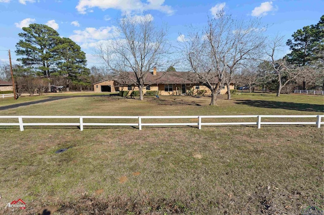 view of front facade with a rural view, a front yard, and fence