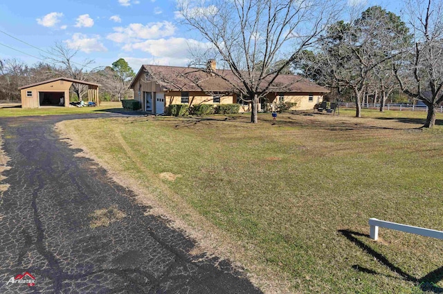 view of front facade featuring a front yard, driveway, and an outbuilding