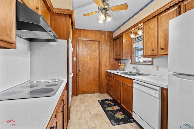 kitchen featuring brown cabinets, light countertops, a sink, white appliances, and under cabinet range hood