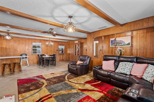 living room with beam ceiling, a dry bar, visible vents, wood walls, and a textured ceiling