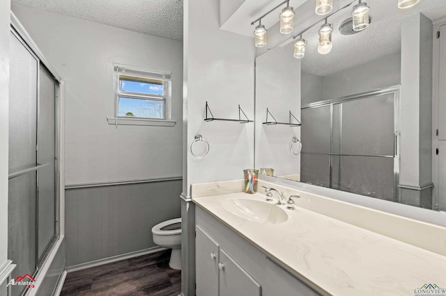 full bath featuring wainscoting, toilet, wood finished floors, a textured ceiling, and vanity