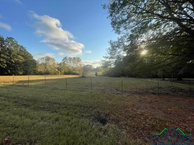 view of yard with fence and a rural view