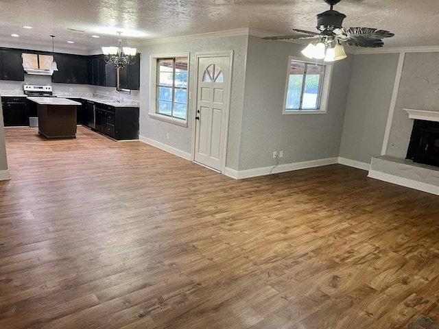 unfurnished living room with crown molding, plenty of natural light, and ceiling fan with notable chandelier