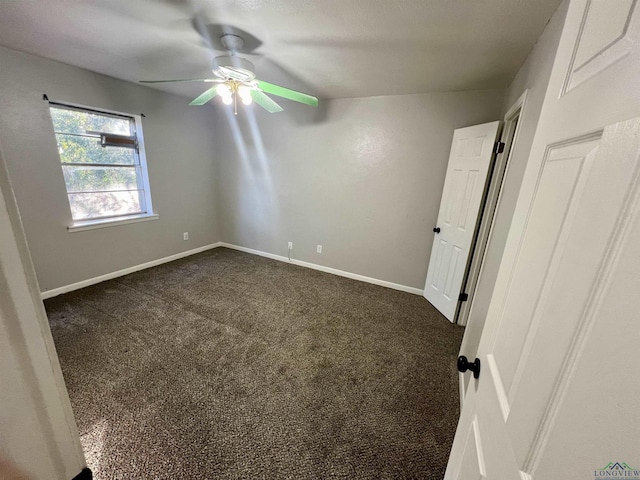 unfurnished room with ceiling fan and dark carpet