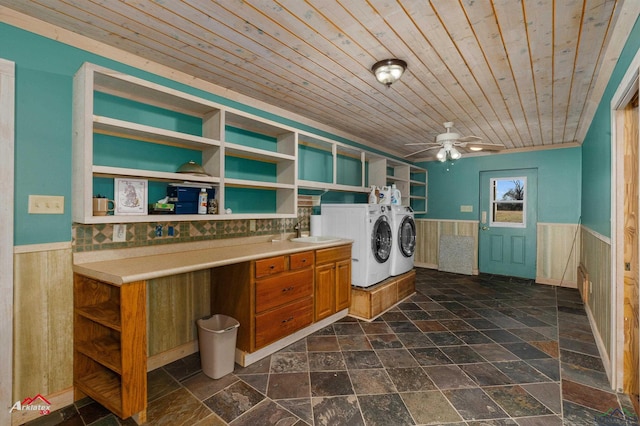 laundry area with wood ceiling, ceiling fan, sink, independent washer and dryer, and wood walls