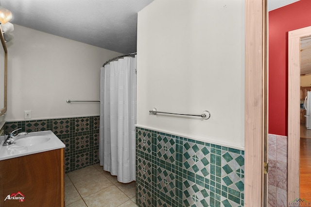 bathroom with a shower with shower curtain, a textured ceiling, vanity, tile walls, and tile patterned flooring