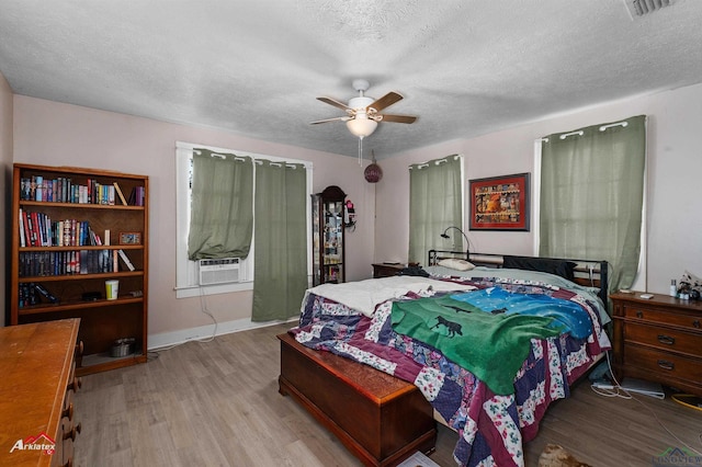 bedroom featuring a textured ceiling, light wood-type flooring, ceiling fan, and cooling unit